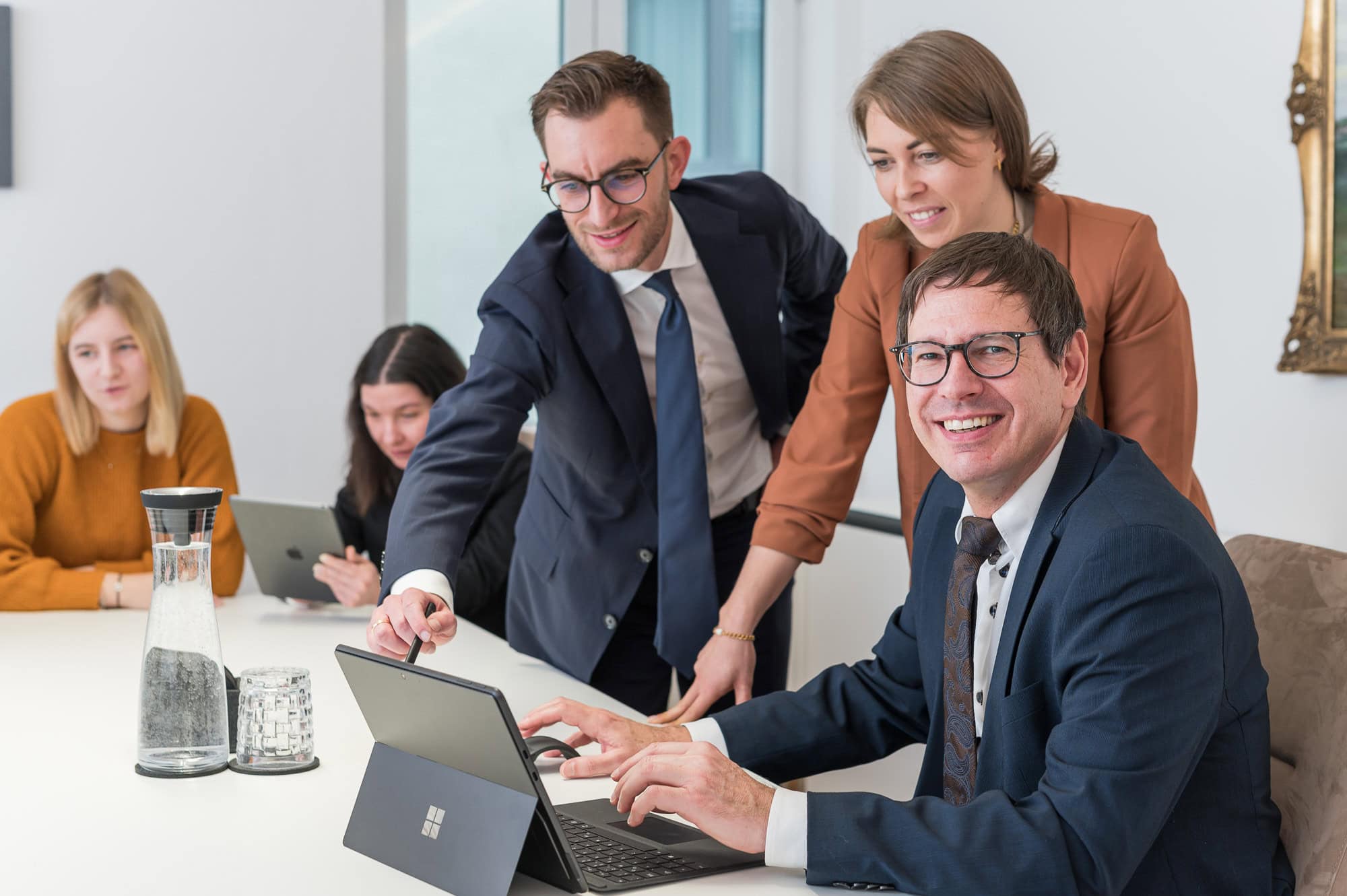 Dieses Businessfoto von Mica Zeitz zeigt ein engagiertes Team in einer modernen Besprechungssituation, ideal für Recruiting in Ingolstadt und Pfaffenhofen. Die professionelle Atmosphäre und die Interaktion der Mitarbeiter unterstreichen die Dynamik eines erfolgreichen Unternehmens.