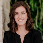 Das professionelle Portrait von Julia Christoph, fotografiert von Mica Zeitz, zeigt eine selbstbewusste Frau vor einer grünen Wand, die sowohl Expertise als auch Vertrauenswürdigkeit ausstrahlt. Ideal für LinkedIn und geschäftliche Profile, spiegelt dieses Bild die Werte von StrategieVier wider.